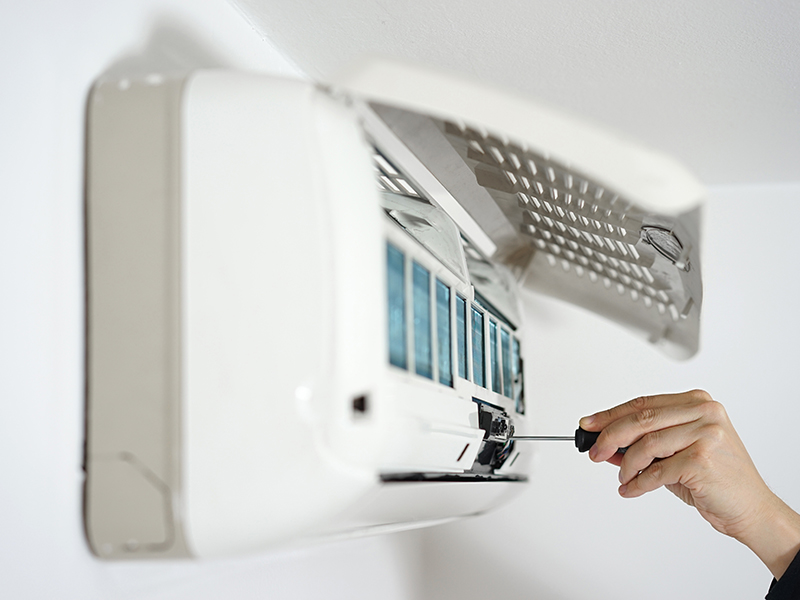 hvac-technician-hand-with-screwdriver-installing-ac-unit-at-wall-many-la